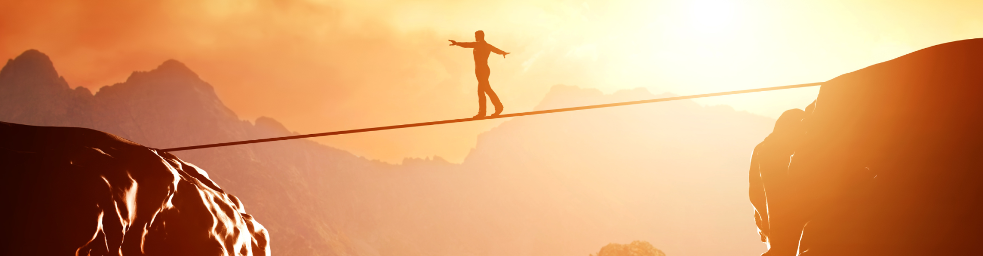 Person walking on a tightrope between two large rocks.