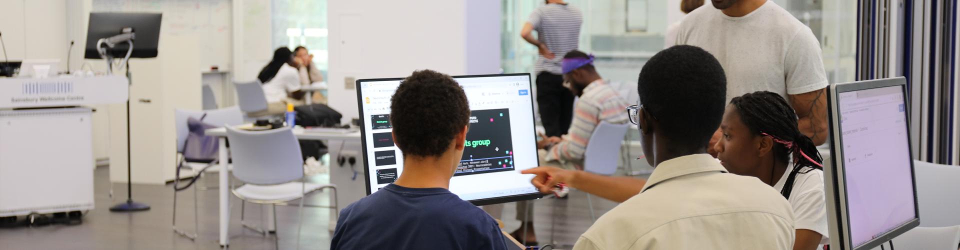 Three students and a teacher gathered around a computer during the Neuronauts summer camp