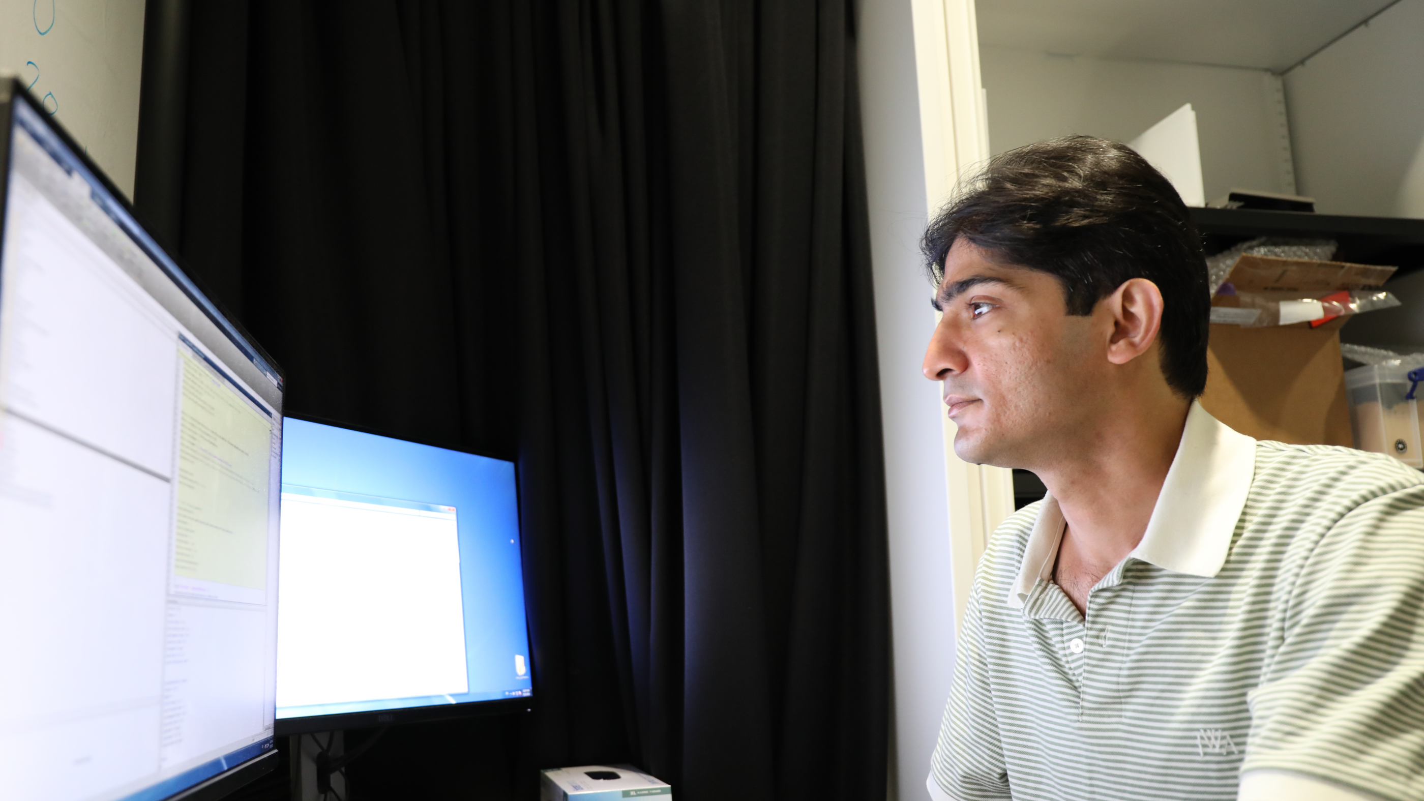 Photo of Dr Mehran Ahmadlou looking at two screens in the lab at SWC