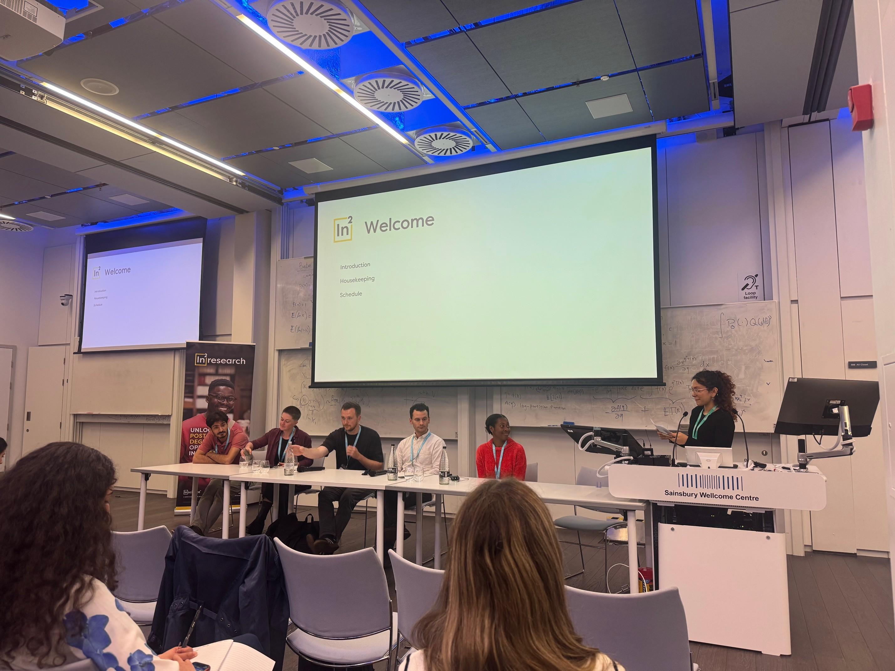 Photo of the panel at the front of the lecture theatre in the Sainsbury Wellcome Centre for the In2research alumni event