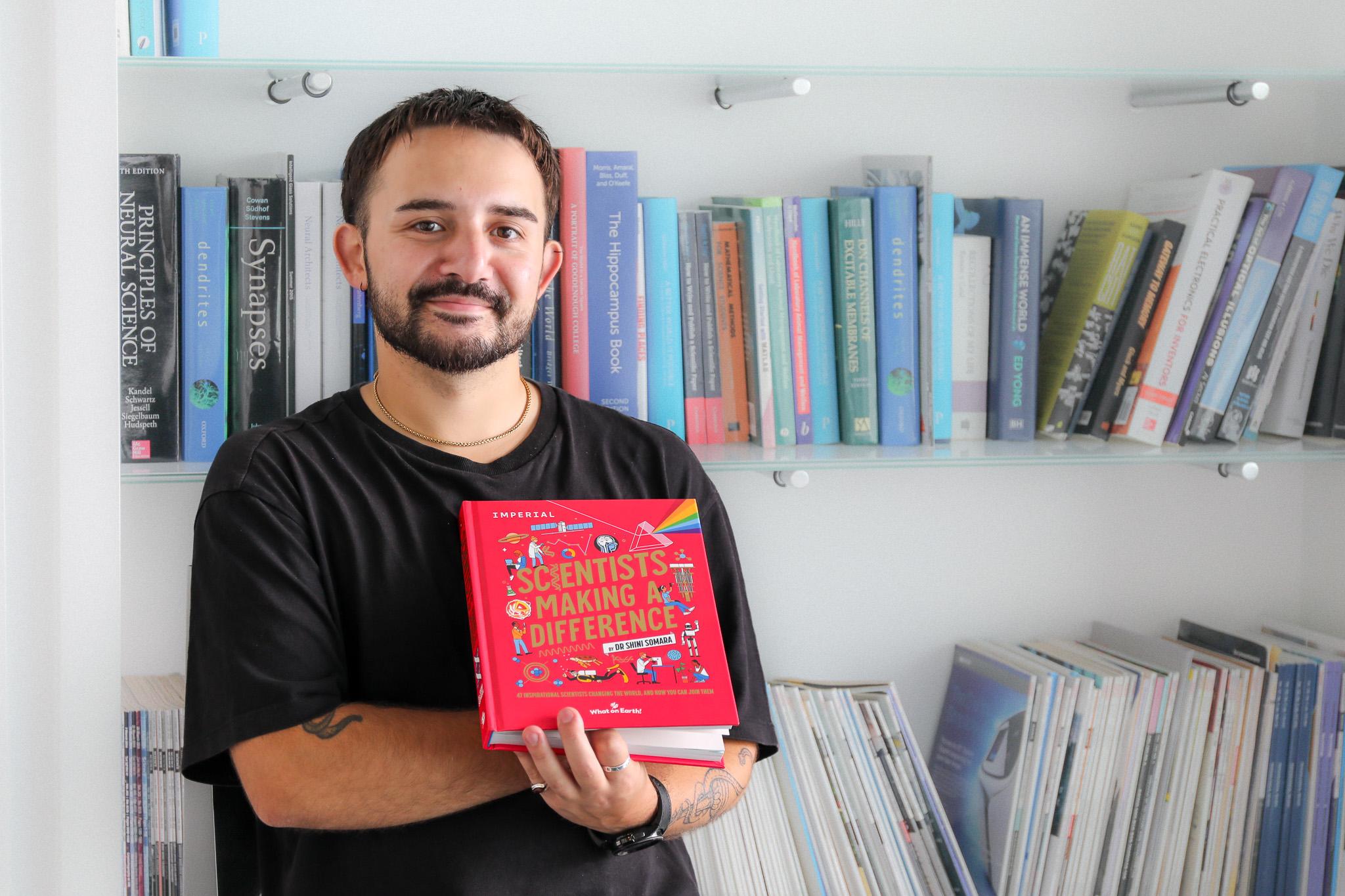 Ryan Cini, Research Technician and SWC holding a book 'Scientists Making A Difference'