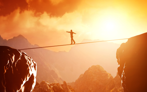 Person walking on a tightrope between two large rocks.
