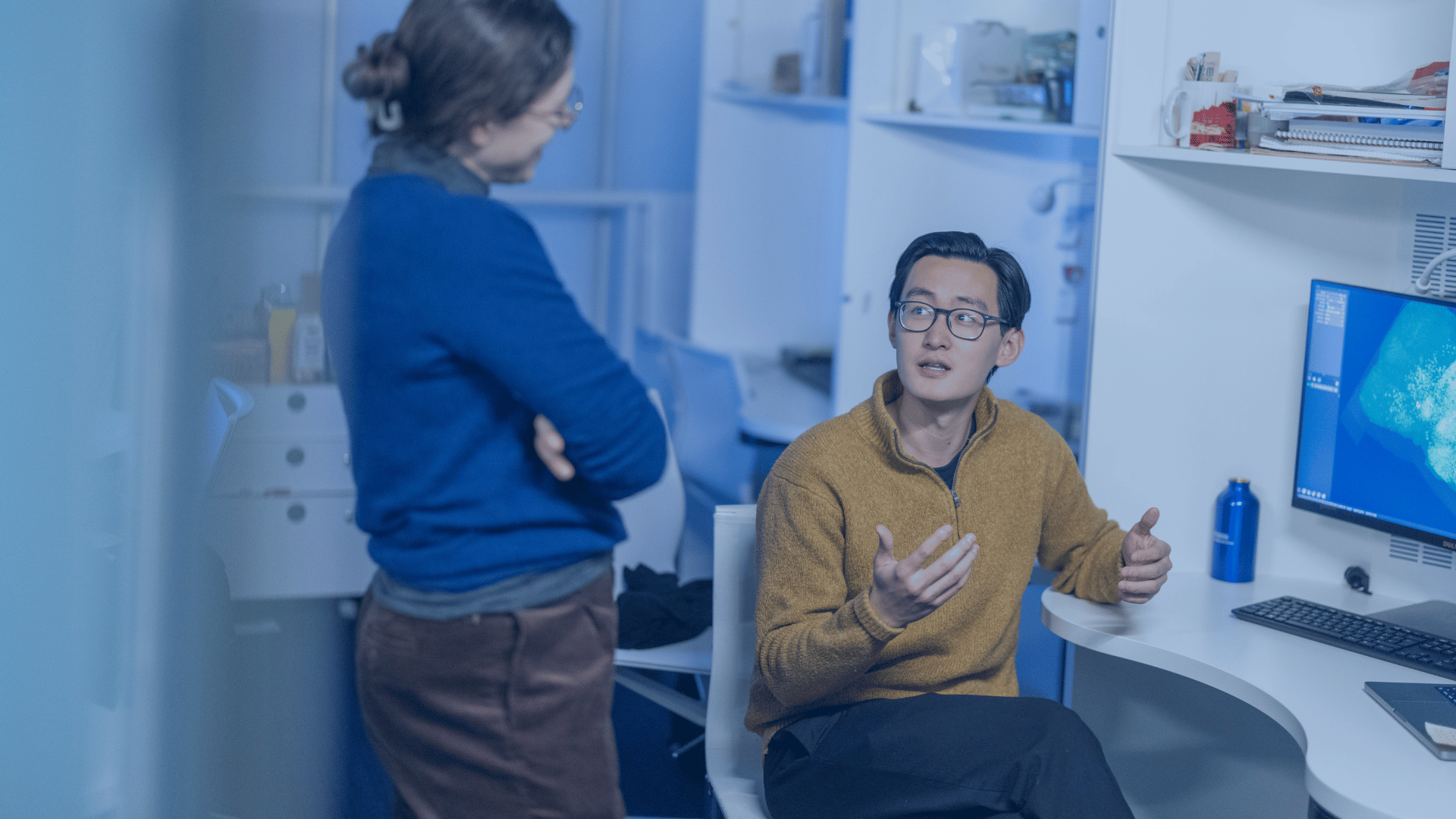 Two neuroscientists collaborating next to a screen with a brain on