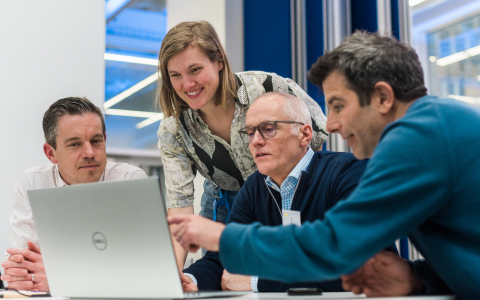 Teachers and students gathered around laptop